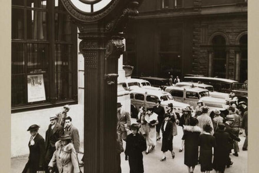 People walk past a clock tower.